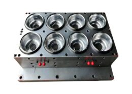 Custom thermoforming mold for transparent disposable plastic cups and lids on factory floor.